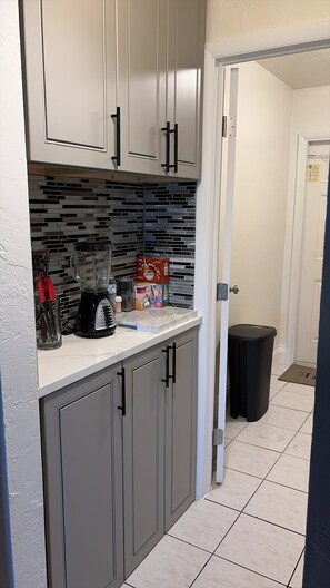 Una cocina con gabinetes grises, una licuadora negra y un salpicadero de azulejos.
