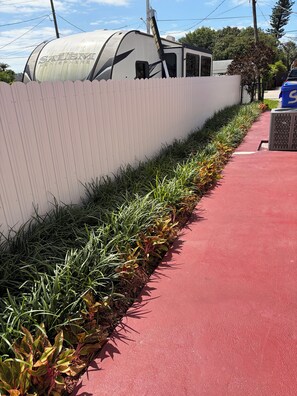 Un chemin rouge longe un mur blanc, et une remorque est stationnée à proximité, portant l’inscription « SALLEM HEMISPHERE ».