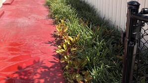 Un sendero rojo, una cerca blanca de piquetes y un panel solar en un edificio.