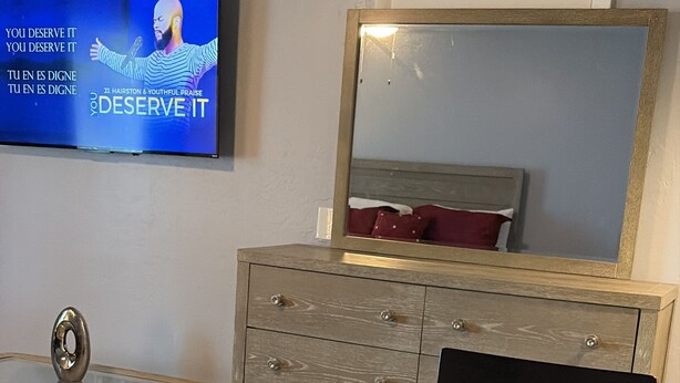 Un comedor con una mesa preparada para dos personas, un televisor montado en la pared y un espejo sobre la mesa.