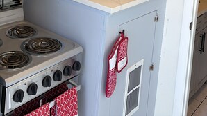 Una cocina con armarios blancos, microondas, estufa y salpicadero de azulejos.