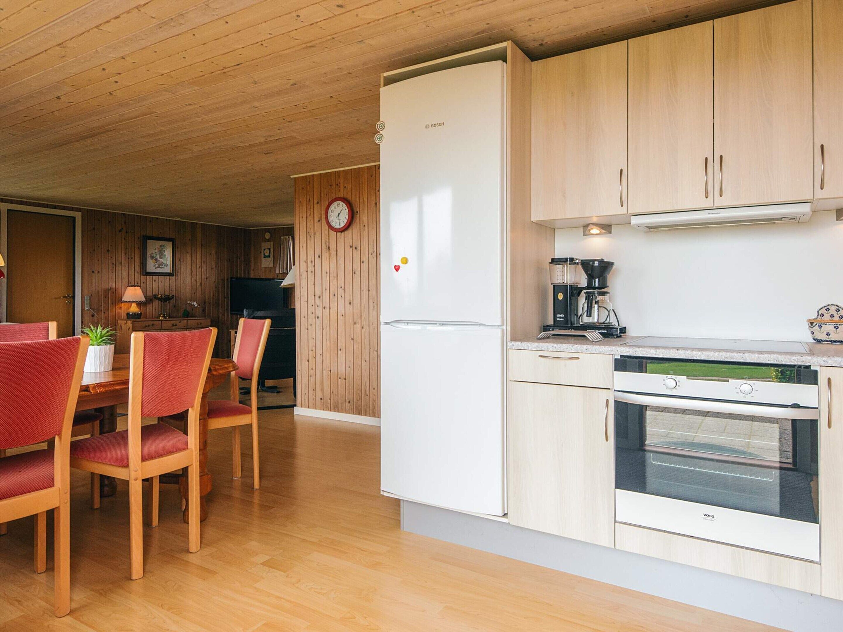 A compact kitchen with a Bosch refrigerator, a coffee maker, and a Voss oven.