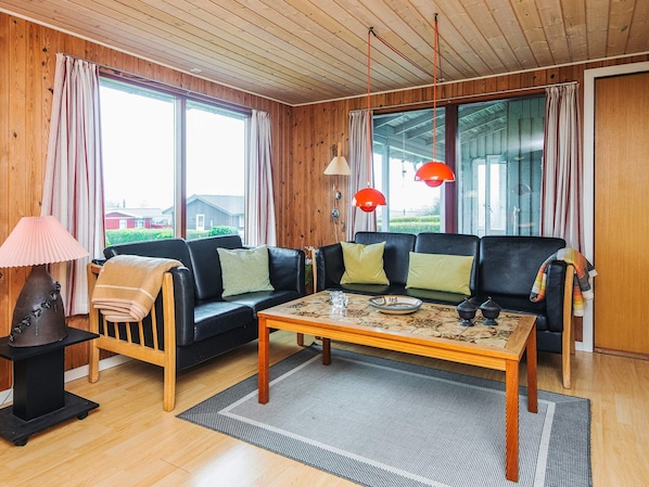 A living room with a sofa, a coffee table, a lamp, and large windows.