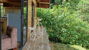 Eine Holzterrasse mit einem Fahrrad, einem rosa Stuhl und einer Glastür zu einem Küchenbereich.
