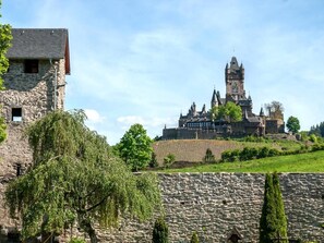 A historic stone building with a prominent tower, surrounded by greenery and a stone wall. - Holiday apartment Lindenplatz in our guesthouse in old town of Zell (Moselle) (Zell (Mosel))