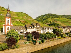 A riverside town with a prominent church, residential buildings, and vineyards. - Holiday apartment Lindenplatz in our guesthouse in old town of Zell (Moselle) (Zell (Mosel))
