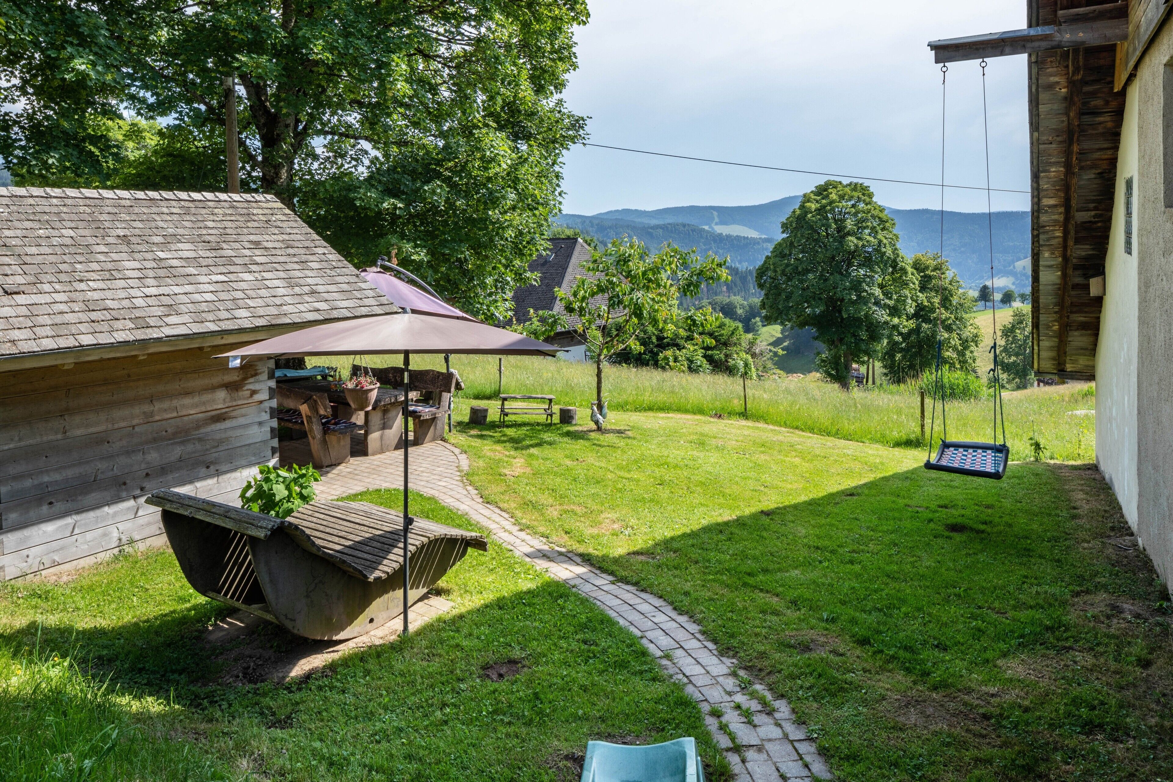 A wooden cabin with a patio, a swing, and a view of distant hills.