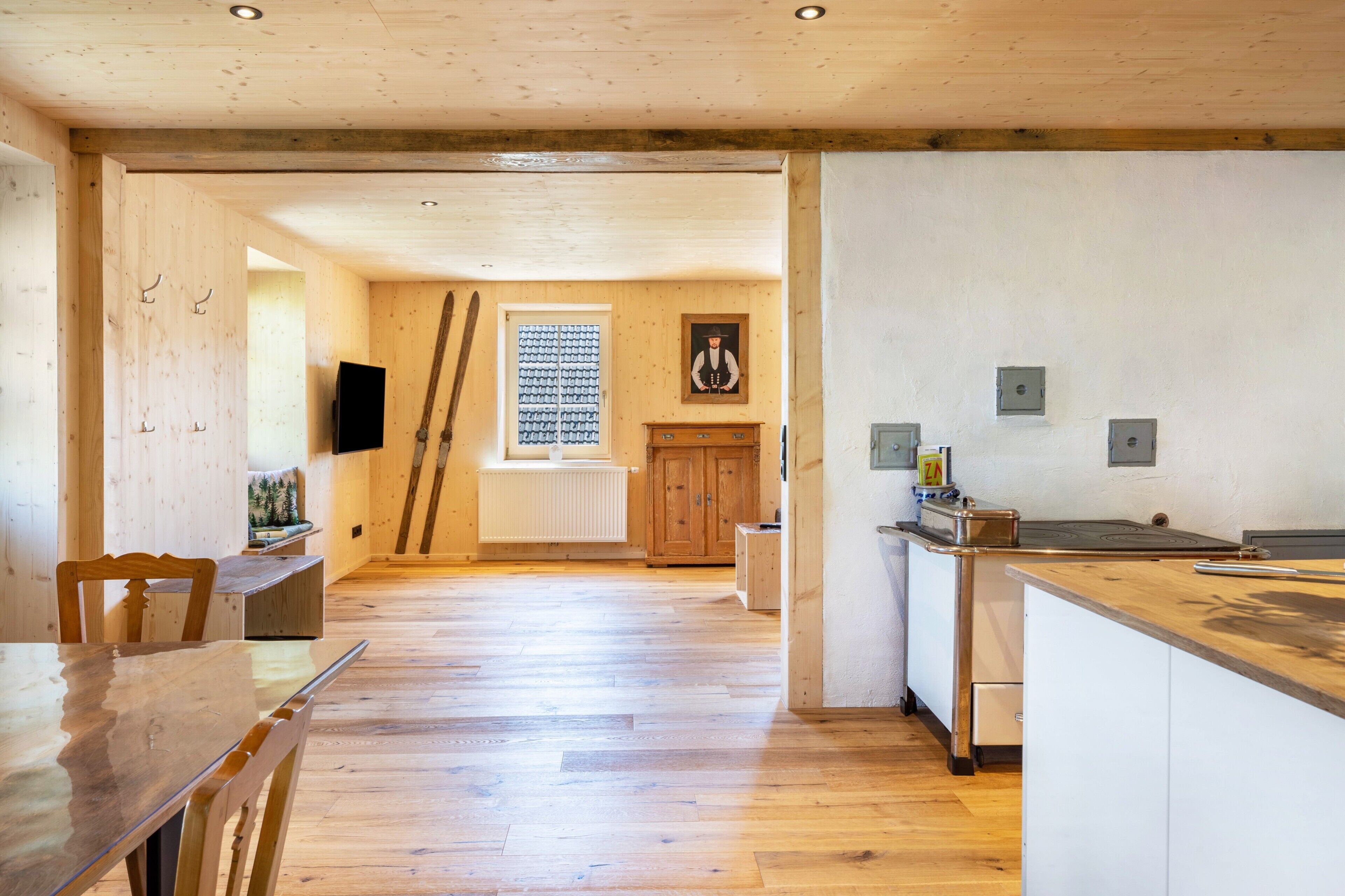 Una cocina amplia con piso de madera, un comedor con mesa y sillas, y vista al área de estar a través de un acceso abierto.