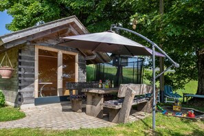 Ein rustikales Holzhäuschen mit einer Terrasse, komplett mit Tisch, Stühlen und einer hängenden Pflanze.
