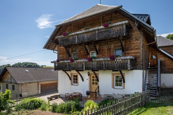 Ein traditionelles Holzhaus mit Balkon, Garage und Treppe.