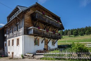 Ein traditionelles Holzhaus mit Balkon, einer Tür und einer kleinen Veranda.