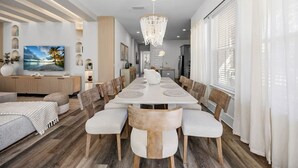 Un espace de salle à manger moderne avec une longue table, des chaises et un lustre.