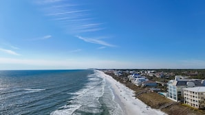 Un hôtel situé sur la côte, avec vue sur la plage, comprenant plusieurs étages et abritant un mélange de logements et de commerces.