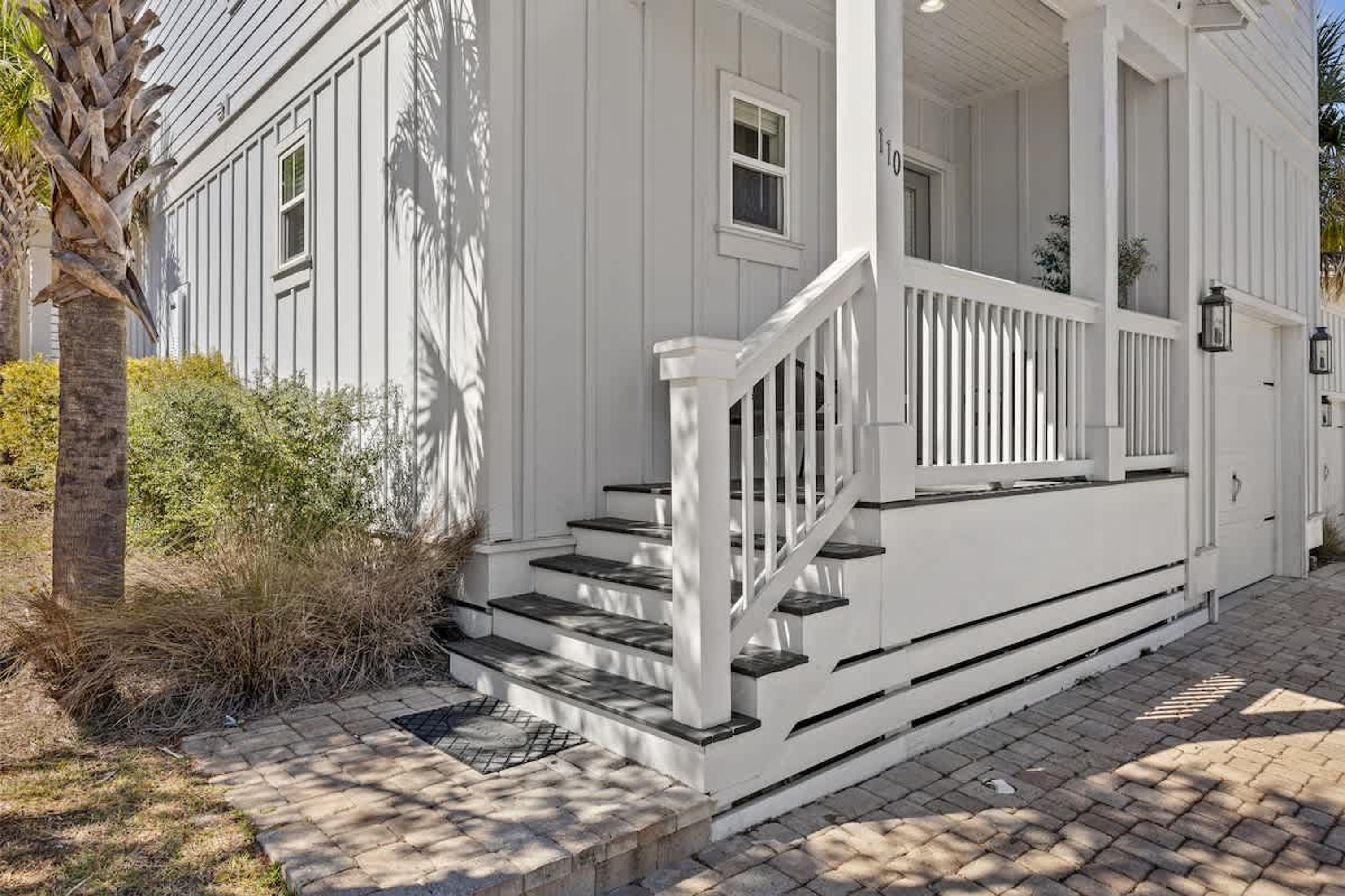 A white house with a porch, steps, and a mailbox.