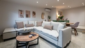 A modern living room with a sectional sofa, a round coffee table, and a dining area with a table and chairs.