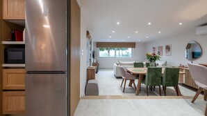 A modern kitchen with a stainless steel refrigerator, wooden cabinets, and a dining area with a table and chairs.