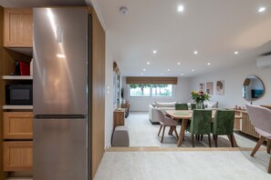 Une cuisine moderne dotée d’un réfrigérateur en acier inoxydable, de meubles en bois et d’un coin repas avec une table et des chaises.