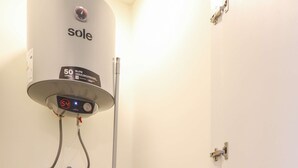 Een wasserette met een voorlader wasmachine, een gestapelde droger en een boiler.