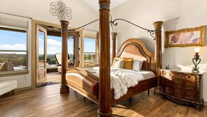 Een hemelbed met uitzicht, een houten dressoir en een plafondventilator.