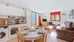 Um espaço de estar compacto com área de jantar, kitchenette e um canto acolhedor para sentar.