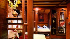 A wooden room with a bed, a shelf with books, and a vase with flowers. - 
Charming Newari-modern homestay in Patan, cozy stay near heritage sites (Lalitpur)