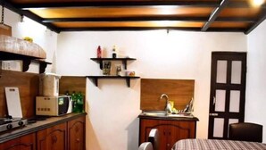 A compact hotel room with a kitchenette, a bed, a chair, and a door. - 
Charming Newari-modern homestay in Patan, cozy stay near heritage sites (Lalitpur)