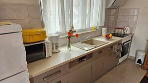 Una cuina moderna amb forn integrat, microones i cafetera.