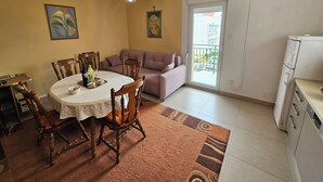 Zona de menjador amb taula rodona, cadires, sofà i un balcó amb vistes.