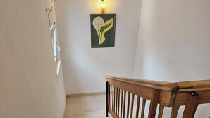 Una escala amb barana de fusta, una làmpada de paret i una obra d'art emmarcada.