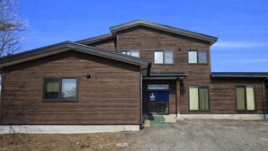 A two-story building with a wooden facade, a front entrance, and a visible flag. - YORIDOKORO (Oma)