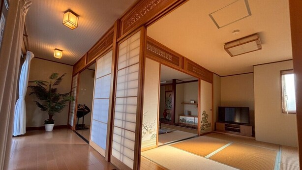 A traditional Japanese room with tatami flooring, sliding doors, and a television.