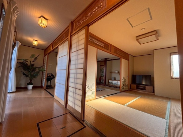 A traditional Japanese room with tatami flooring, sliding doors, and a television.