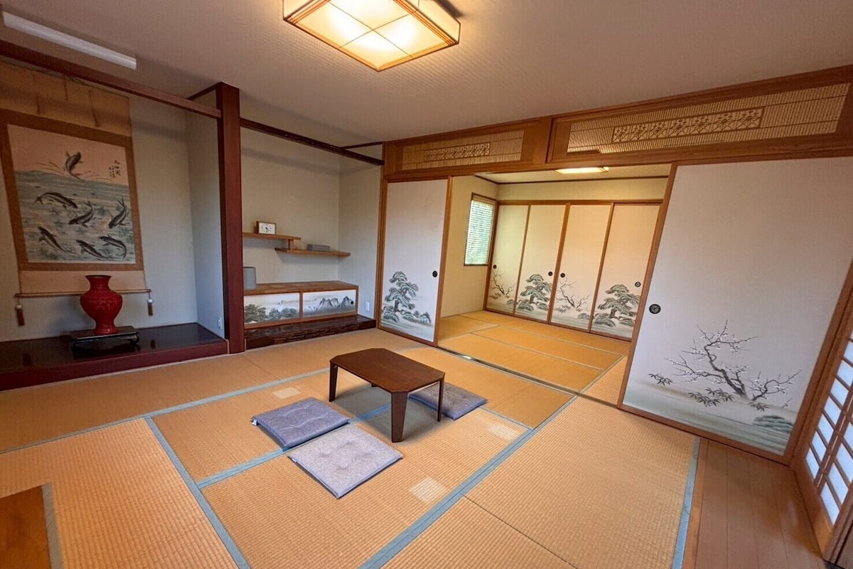 Una habitación japonesa tradicional con suelo de tatami, una mesa de madera baja y puertas correderas con motivos artísticos.