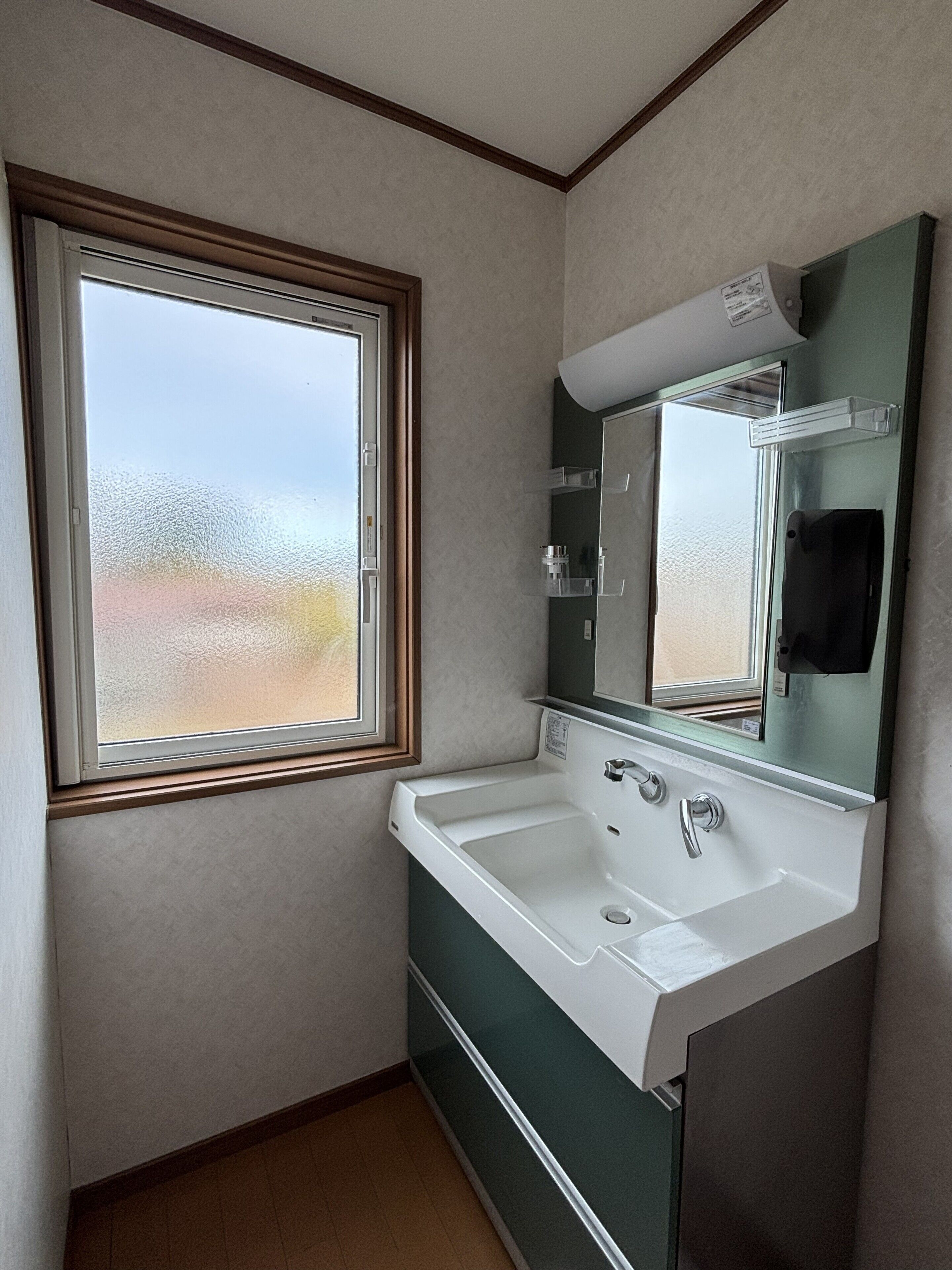A small bathroom with a window, a sink, and a mirror.