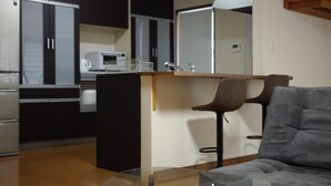 A modern kitchen with a central island, bar stools, and a sofa in a living area.