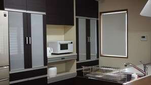 A modern kitchen with dark cabinets, a microwave, a coffee maker, and a sink. - YORIDOKORO (Oma)