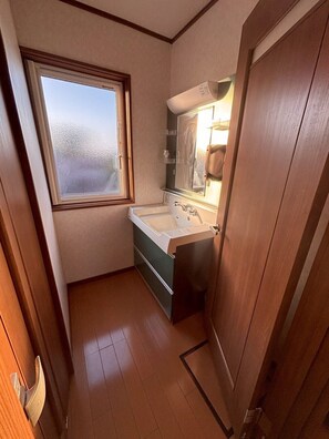 Un baño pequeño con ventana, lavamanos y espejo.