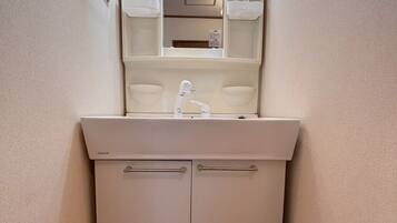 A small bathroom with a white sink, mirror, and a trash bin.