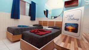 Habitación de hotel con dos camas, un espejo, cabecero de madera, repisa en la pared y un cuadro enmarcado.