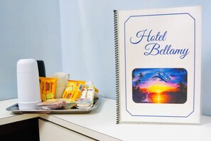 A hotel room with a tray of breakfast items, a coffee maker, and a framed picture of a sunset with dolphins. - Hotel Bellamy (São Paulo)