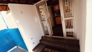 Entrada de hotel con felpudo, una puerta azul y opciones de pago en la puerta.