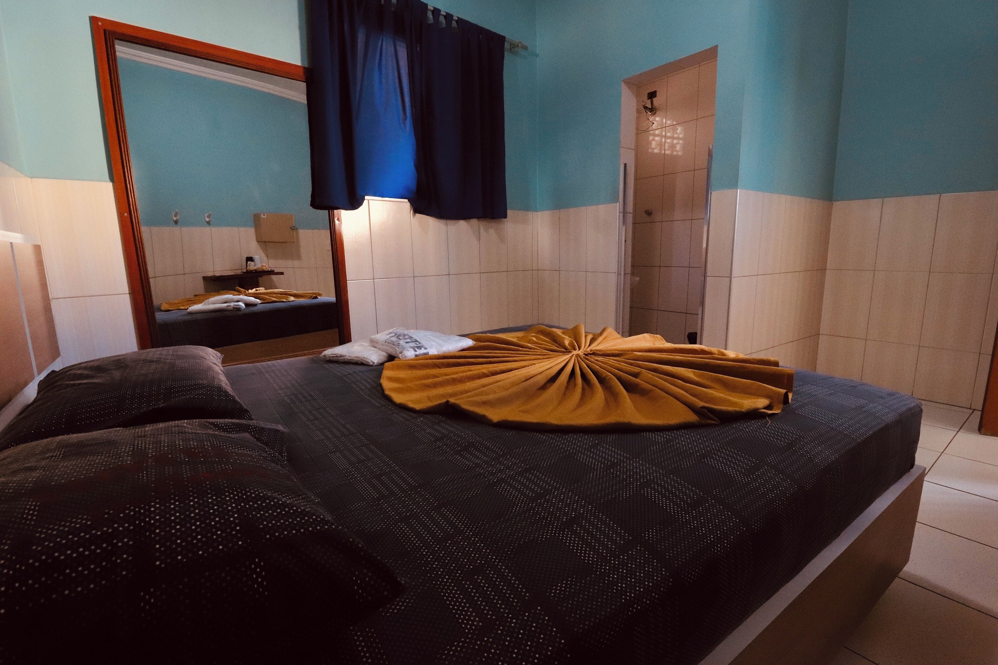 A bedroom with a bed, a mirror, a door, and a towel on the bed.