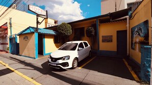 Un coche blanco estacionado frente a un hotel con un cartel que dice 'HOTEL Bellamy'.