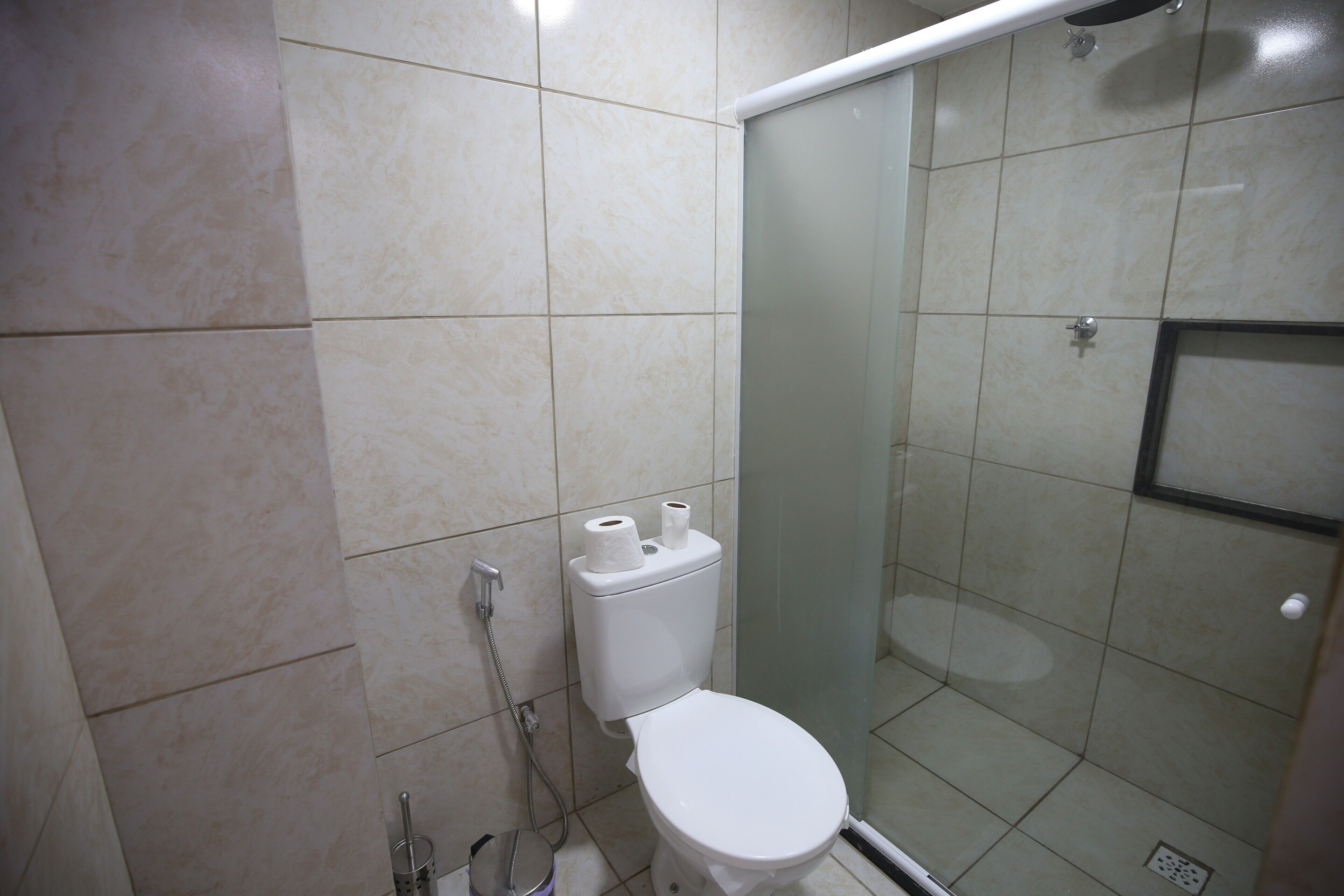 Un baño con inodoro, cabina de ducha y paredes de azulejos.
