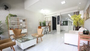 Una sala moderna con una mesa de centro de vidrio, dos sillones, un sofá y una estantería.