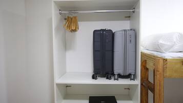 A white wardrobe with two suitcases and a laptop on the shelf.