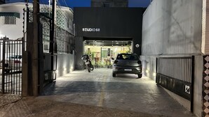 Una entrada con reja a un edificio con la leyenda 'STUDIO 68', con un coche estacionado y una motocicleta en su interior.