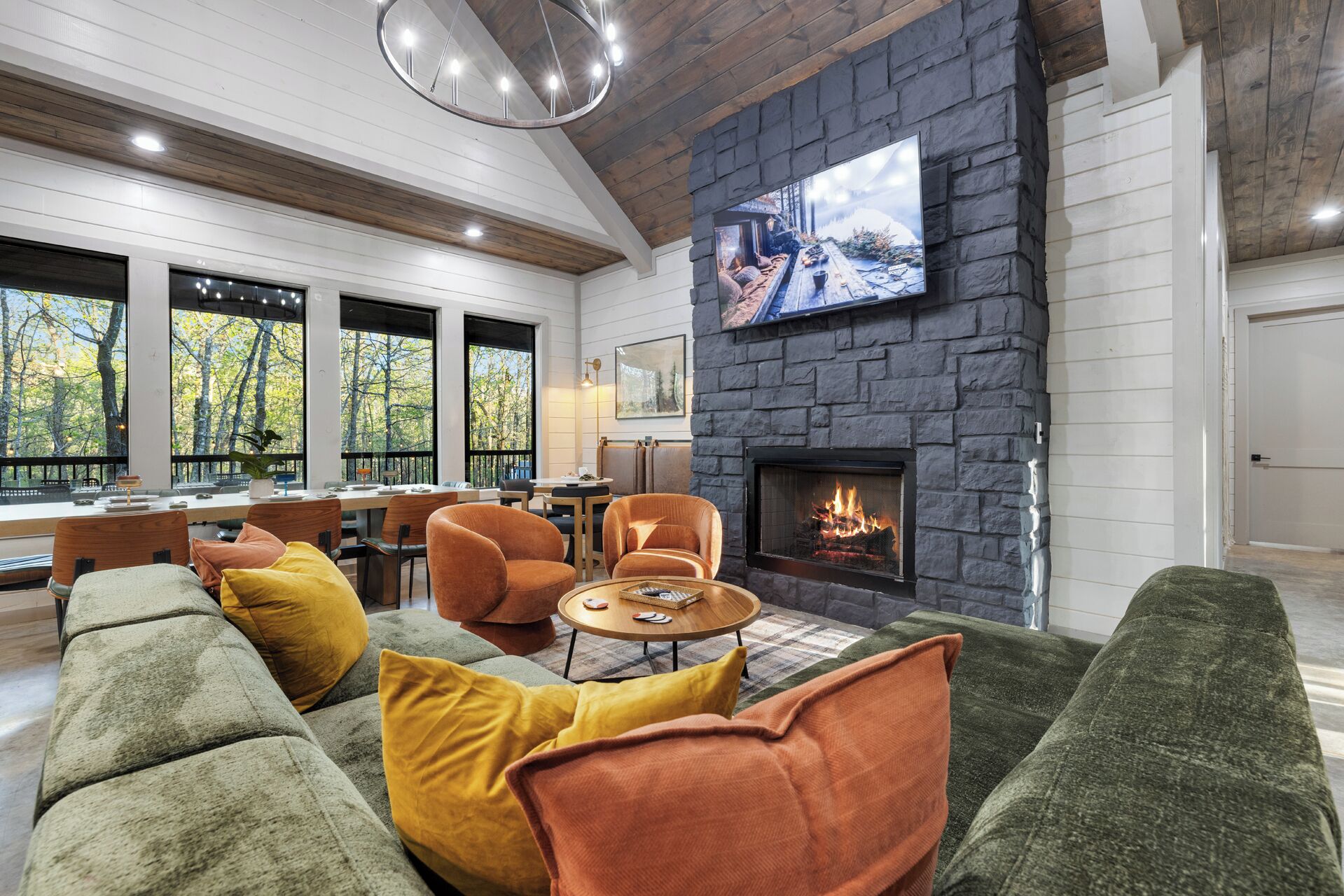 A modern living room with a stone fireplace, large windows, and a cozy seating area.