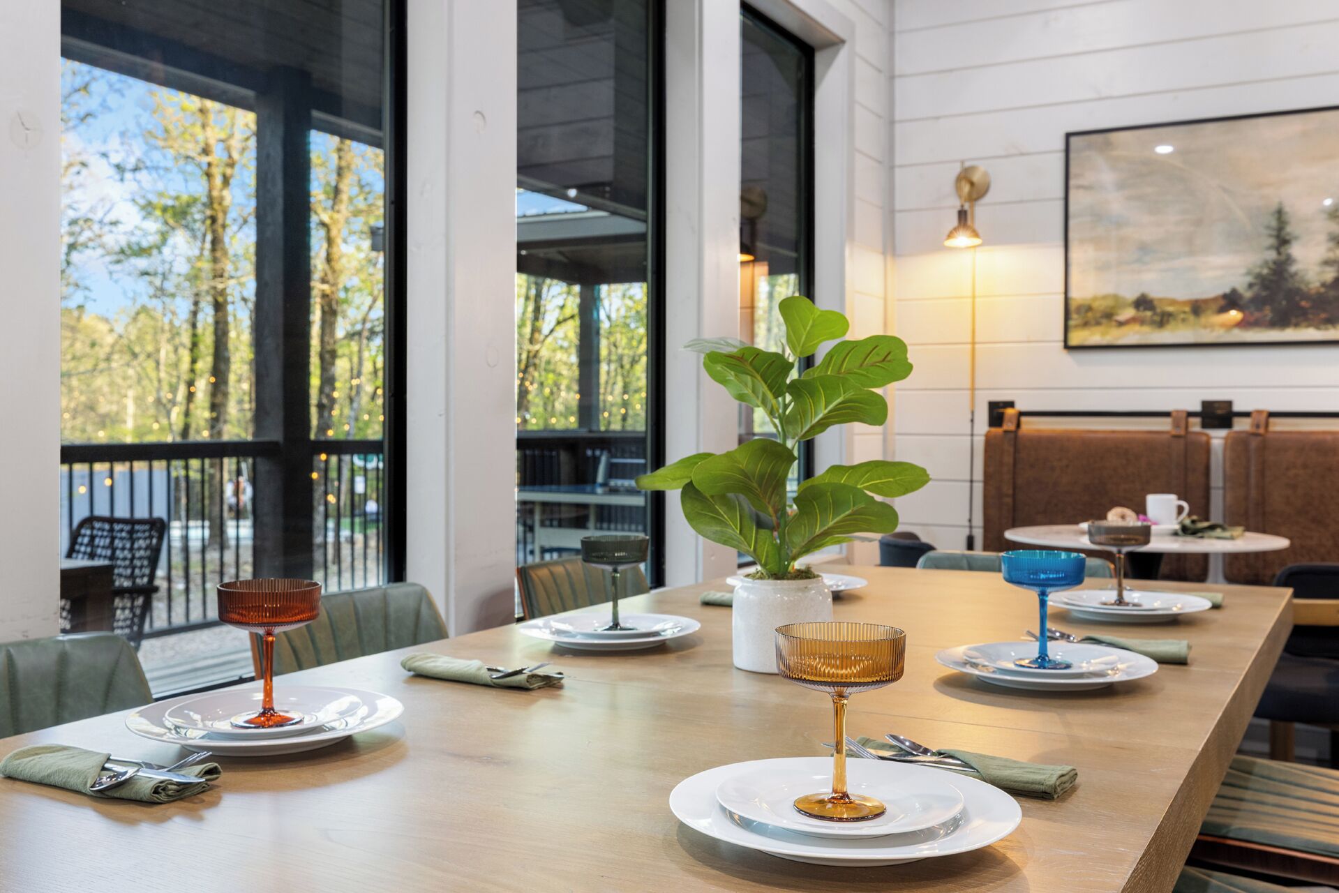 A dining area with a long table, chairs, and a potted plant.