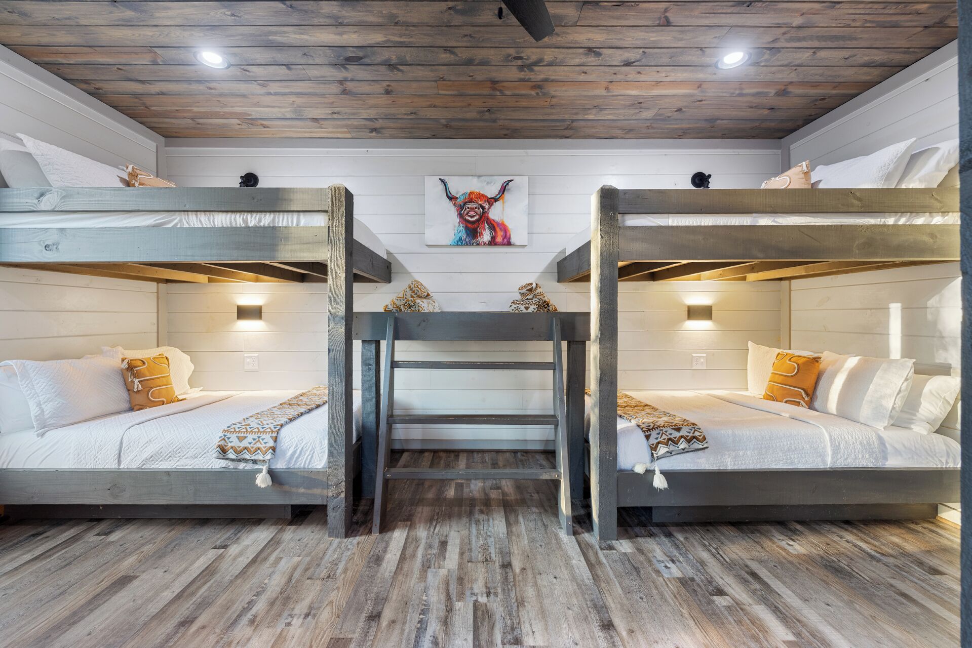 A bunk bed room with wooden floors and a rustic ceiling.